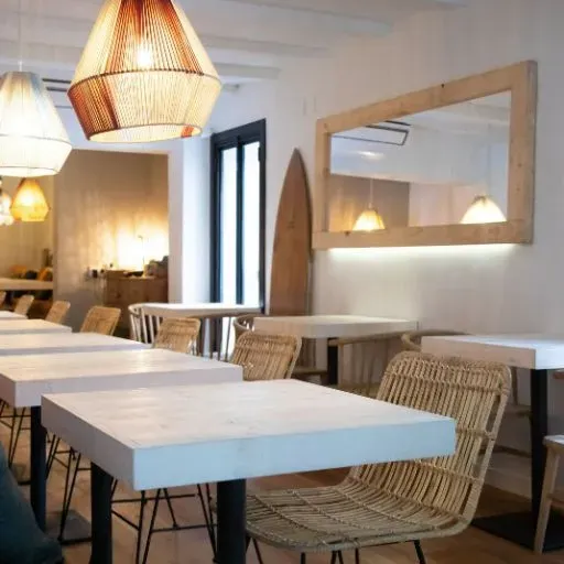 Un restaurante con mesas y sillas y una tabla de surf en la pared.
