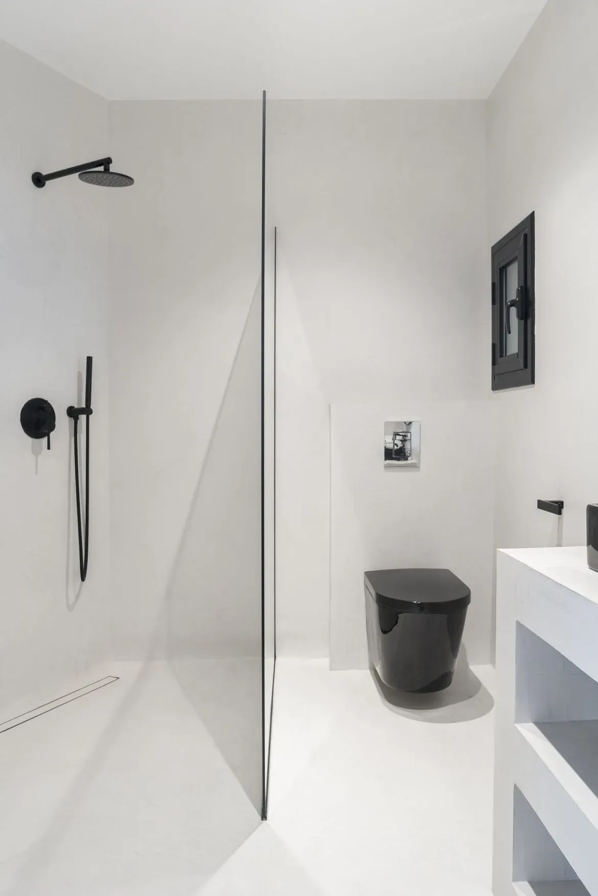 Un baño con inodoro, lavabo y ducha de color negro.