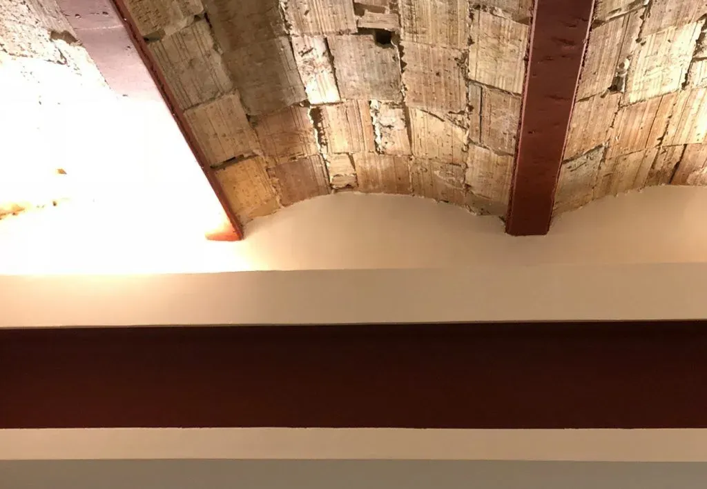 Un techo con arco de ladrillo y vigas de madera.