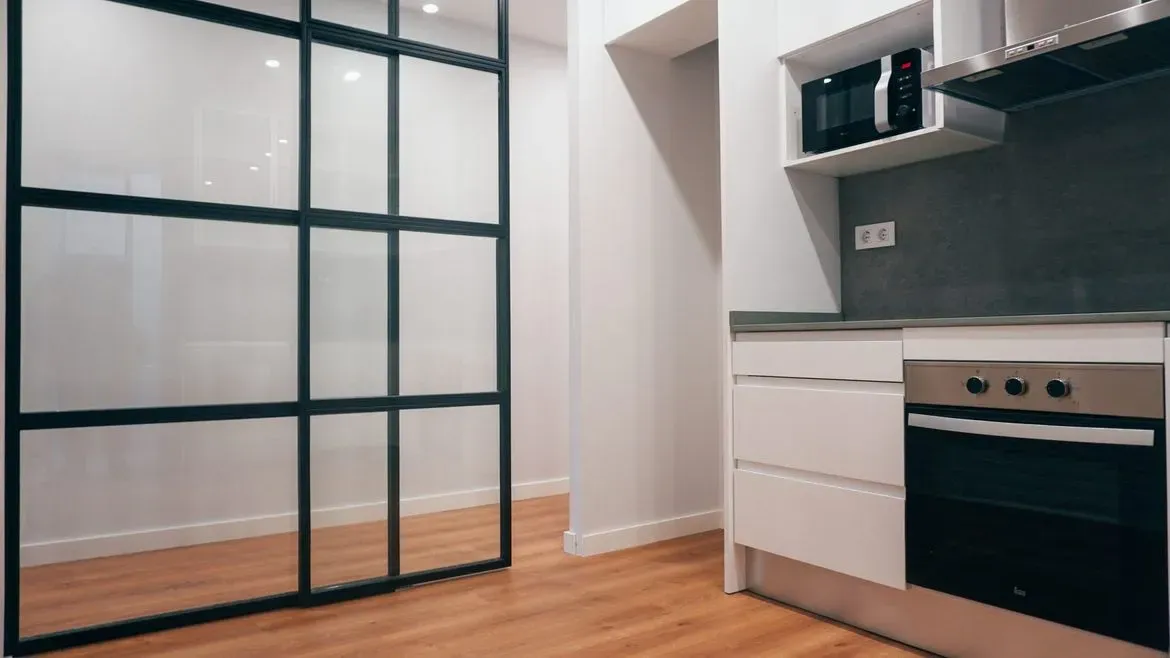 Una cocina con una puerta corrediza de vidrio entre la cocina y el pasillo.