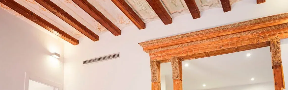Una habitación con un espejo y vigas de madera en el techo.