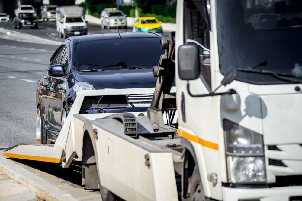 Una grúa está remolcando un automóvil al costado de la carretera.