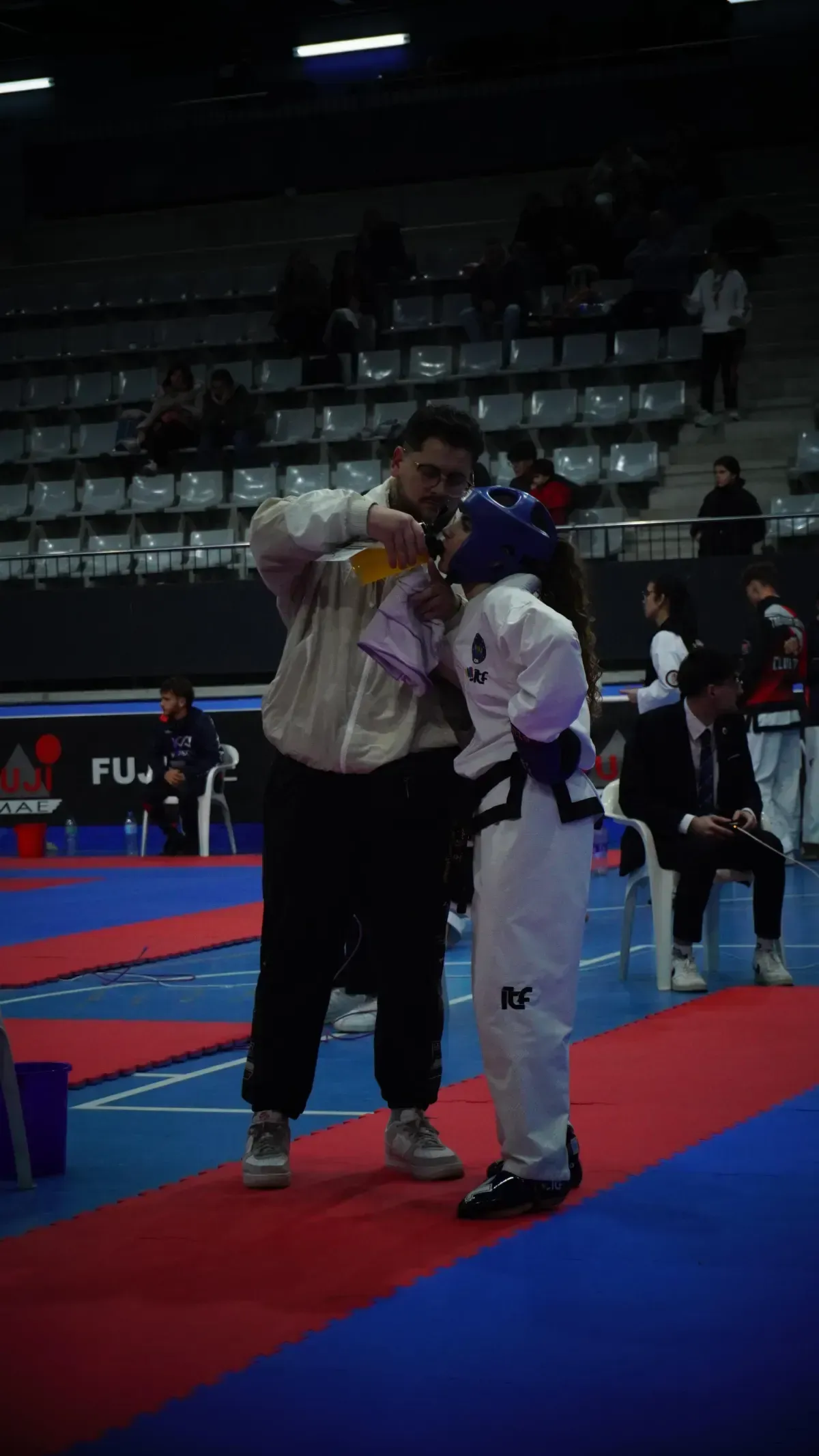 Un entrenador ajusta una medalla de oro alrededor del cuello de un atleta de taekwondo 