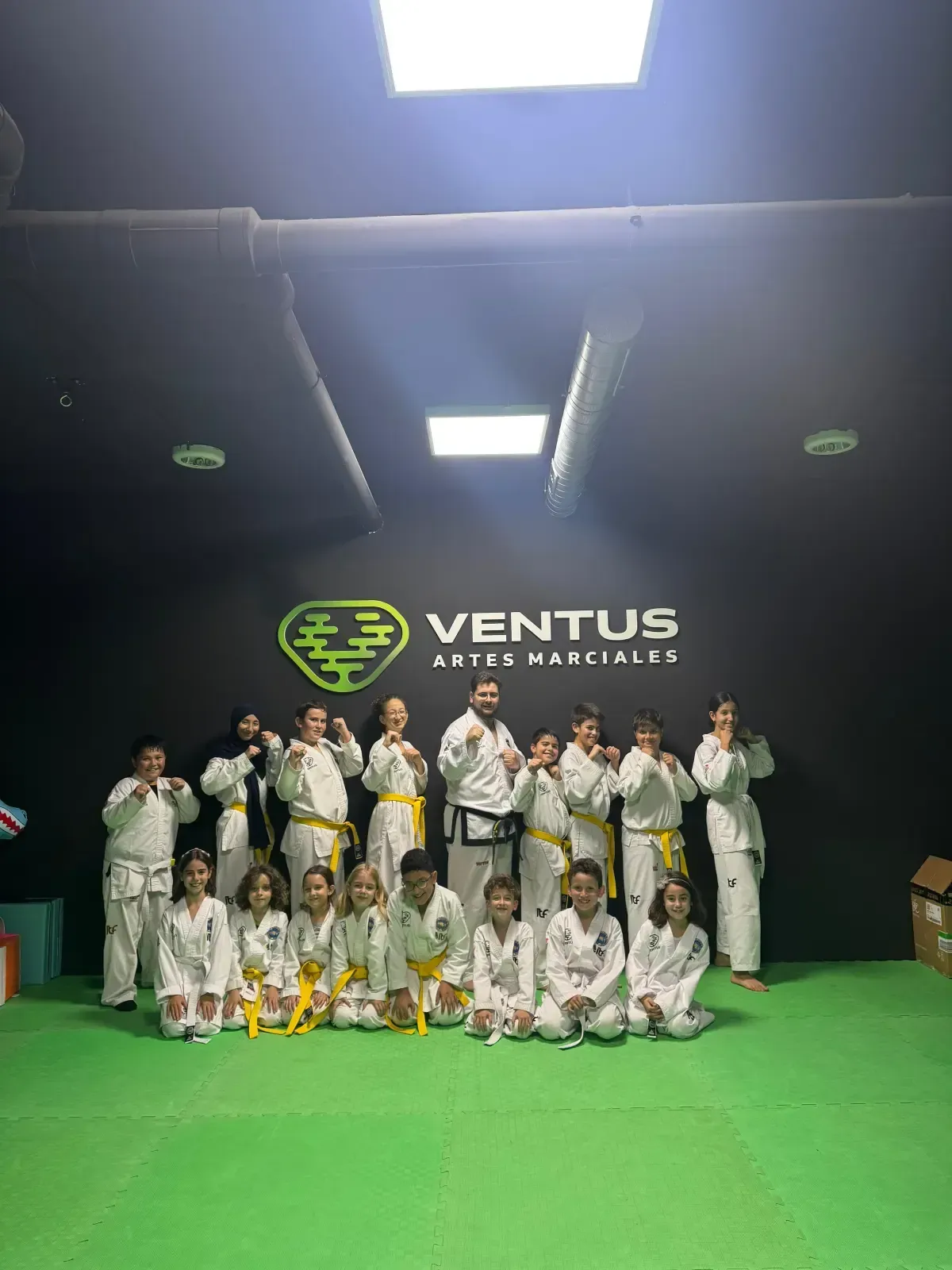 Un grupo de estudiantes y su instructor, vestidos con uniformes de artes marciales