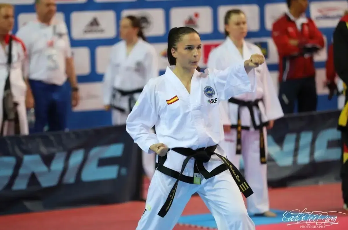 Una persona con un uniforme blanco de taekwondo con un parche de la bandera española realiza un puñetazo
