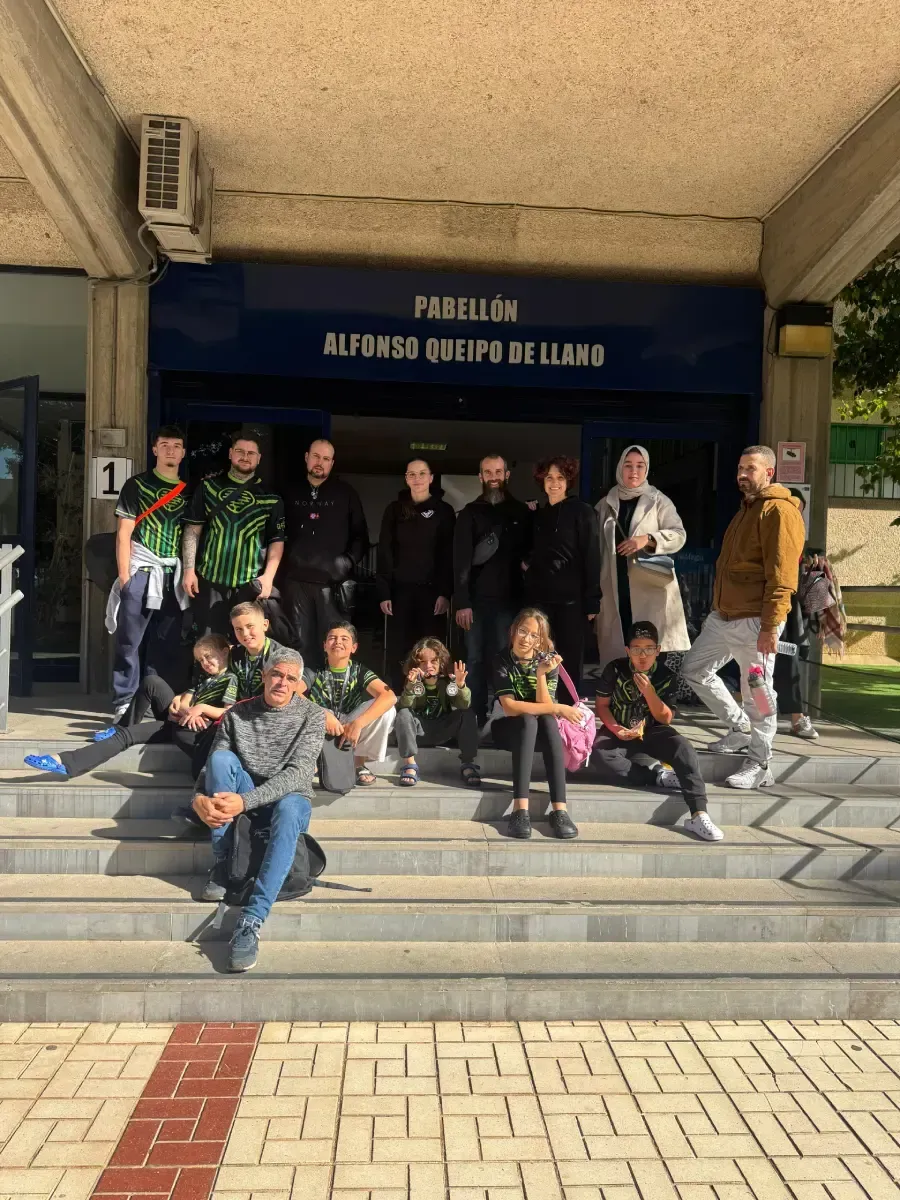 Un grupo de personas con camisetas iguales se encuentra de pie y sentado en las escaleras exteriores