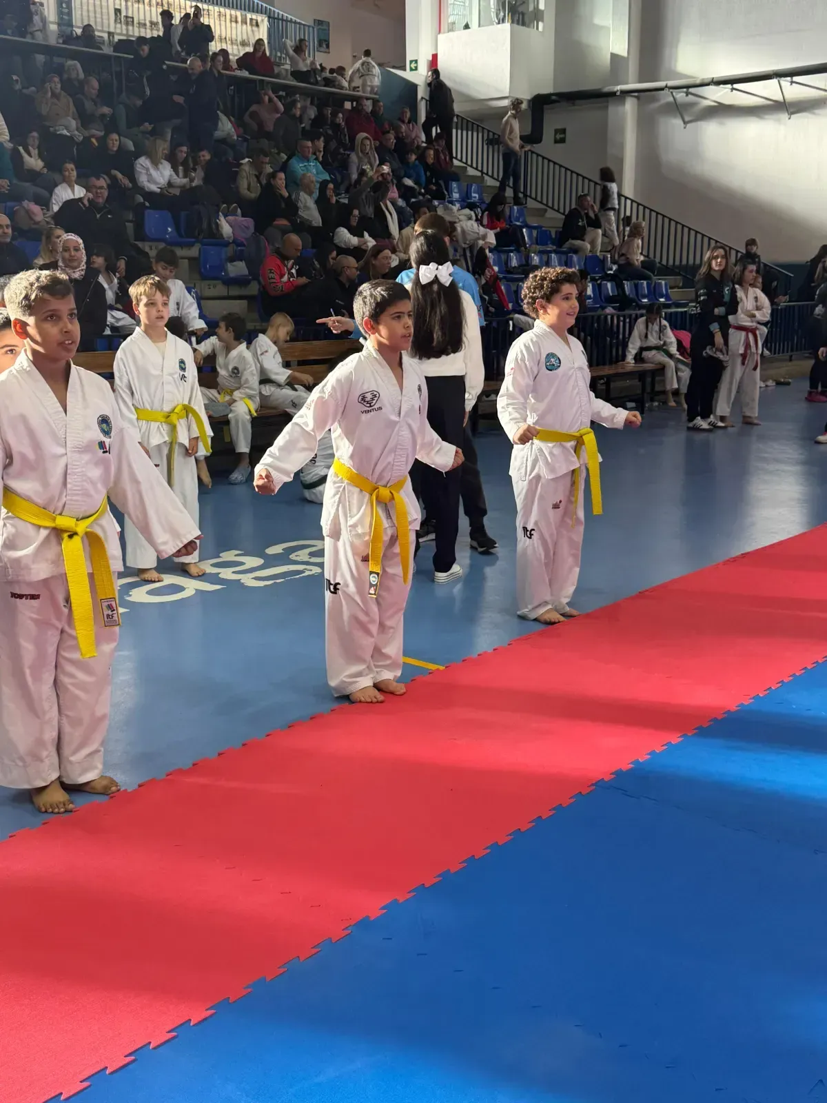 Tres estudiantes de artes marciales, vestidos con uniformes blancos y cinturones amarillos