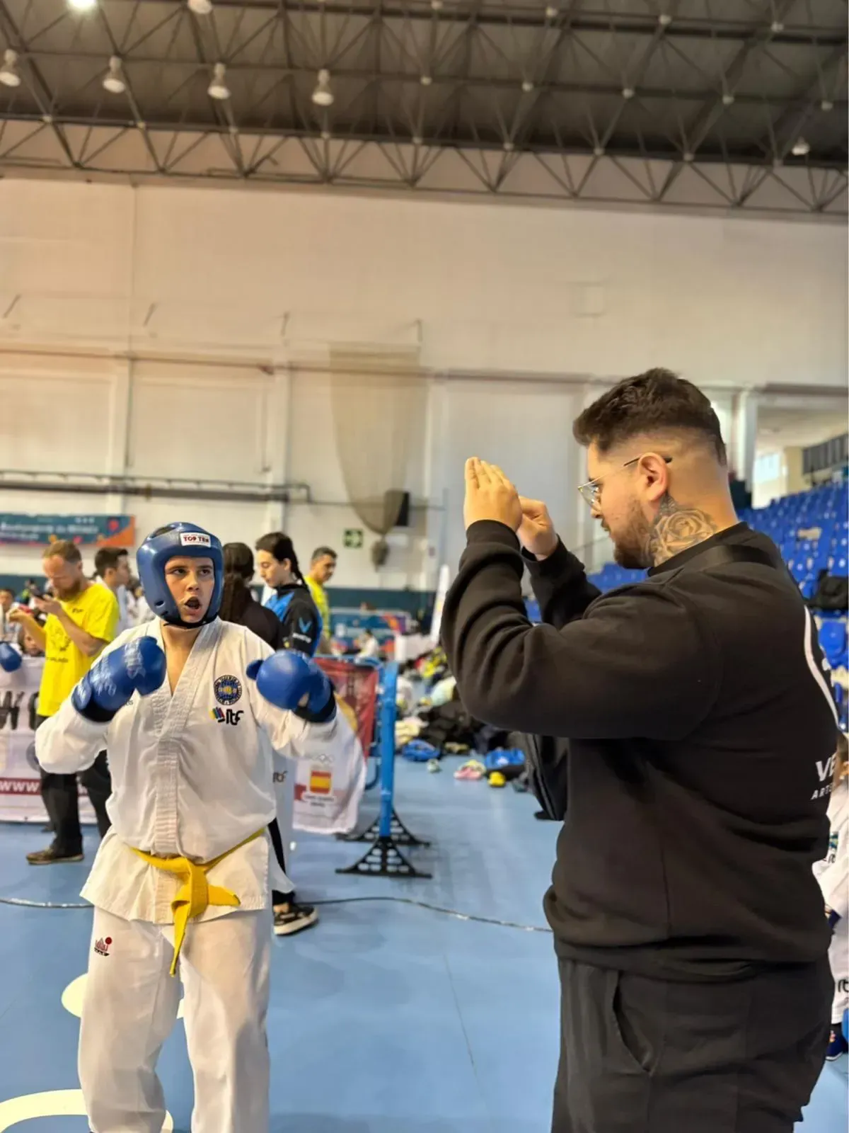 En un gimnasio, un entrenador da instrucciones mediante gestos a un estudiante