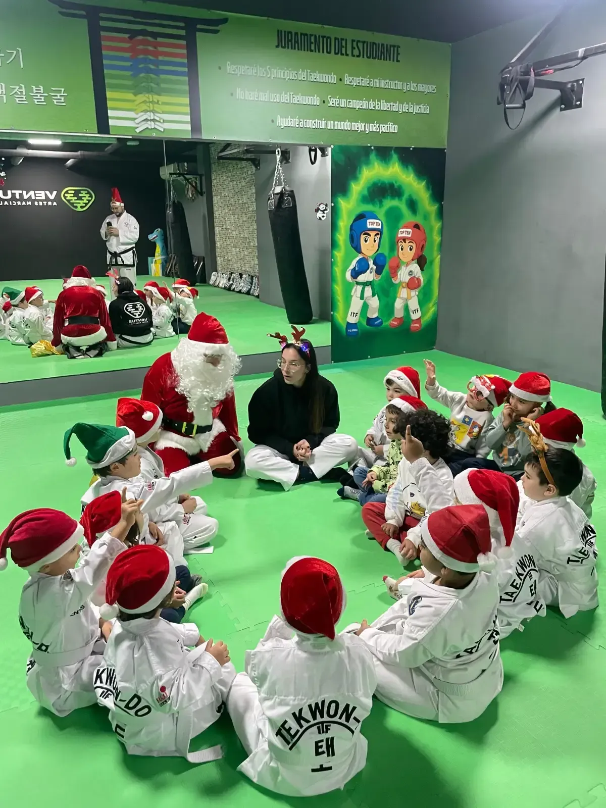 Papá Noel y un grupo de niños con uniformes blancos de taekwondo y gorros de Papá Noel