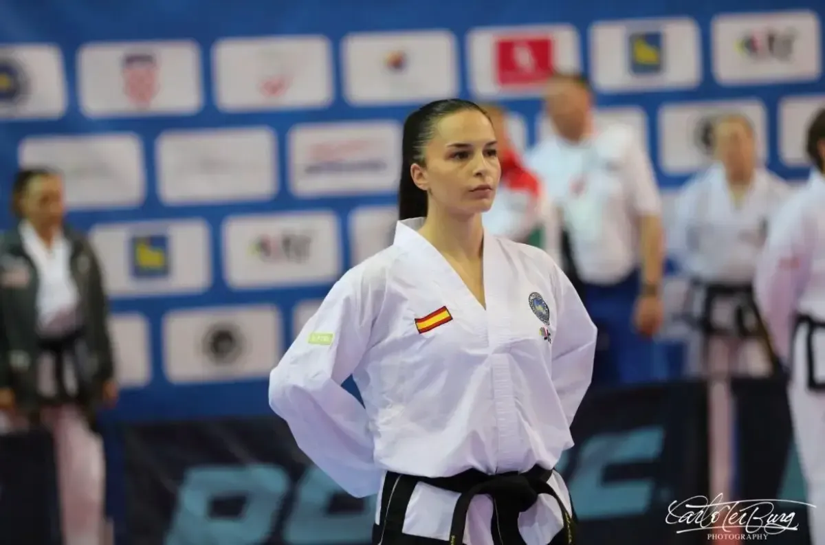 Una persona que viste un uniforme blanco de taekwondo con un parche de la bandera española se encuentra de pie