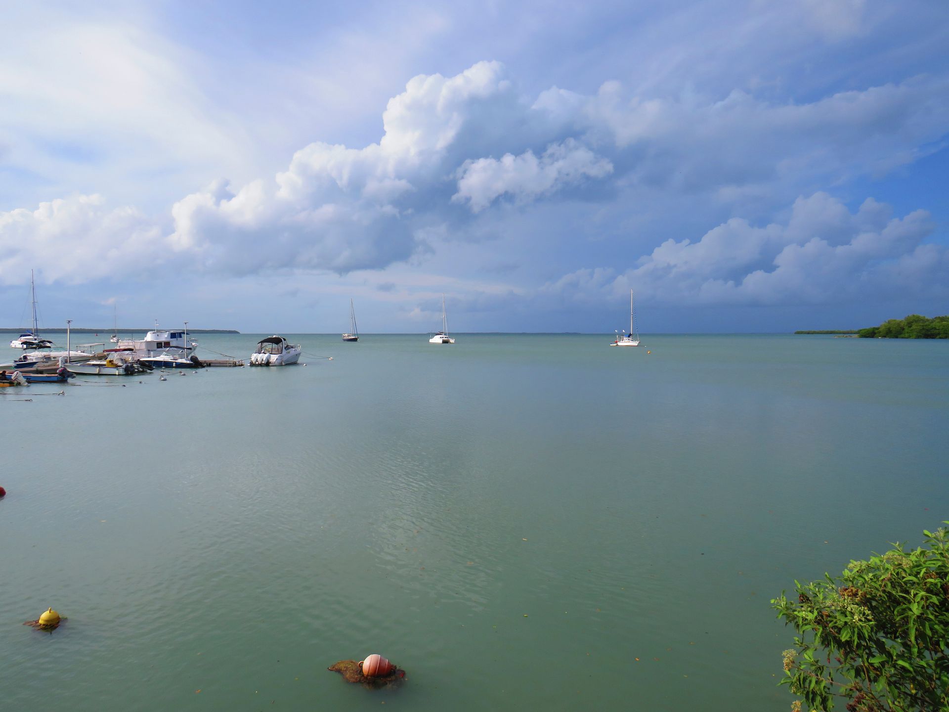 Port paisible avec des bateaux sur une eau bleu-vert sous un ciel nuageux