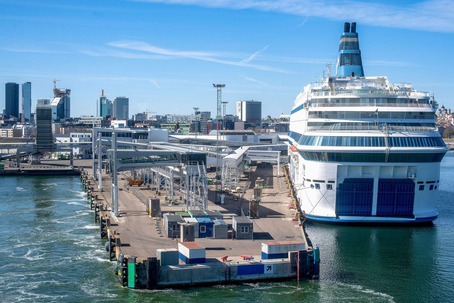 Grand paquebot de croisière amarré à un quai portuaire, avec des immeubles en arrière-plan