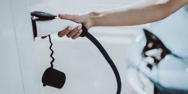 Una persona está cargando un coche eléctrico en una estación de carga.