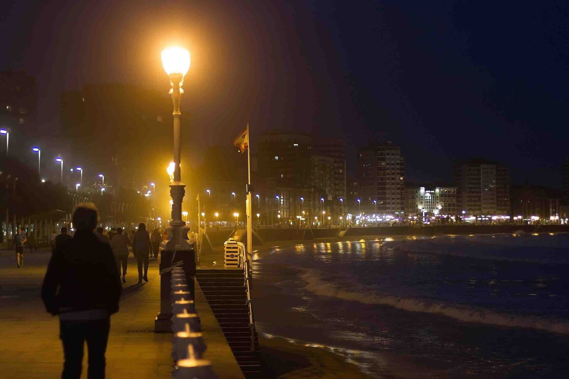 Una persona camina por una acera de noche.