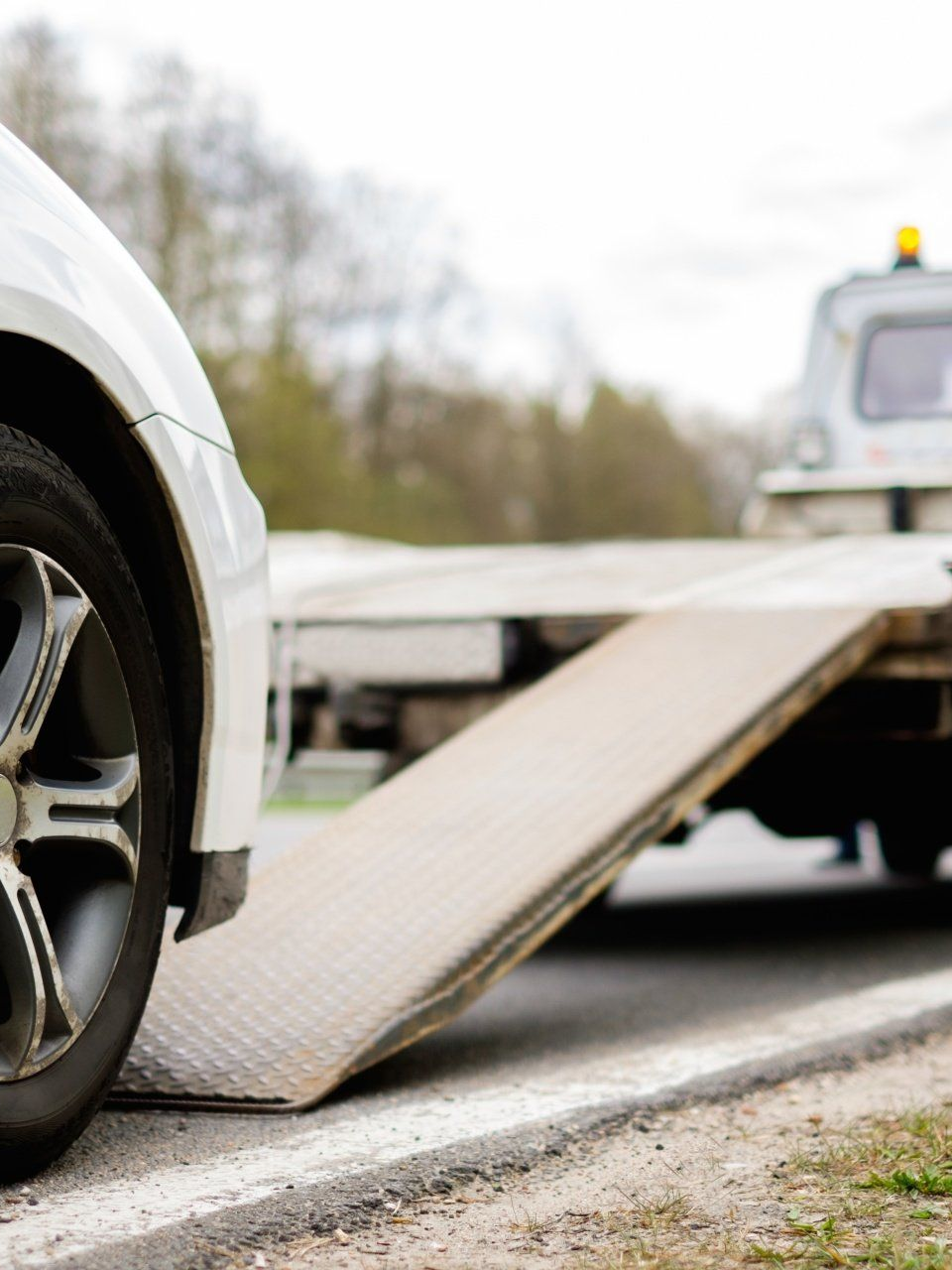 Voiture sur la rampe de remorquage en cours de chargement en bord de route.