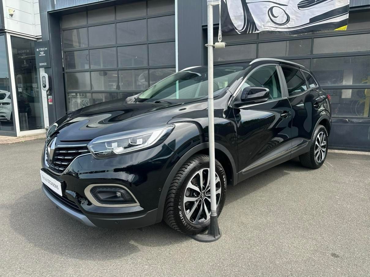Un SUV compact noir est garé devant une concession automobile, un poteau bloquant le capot.