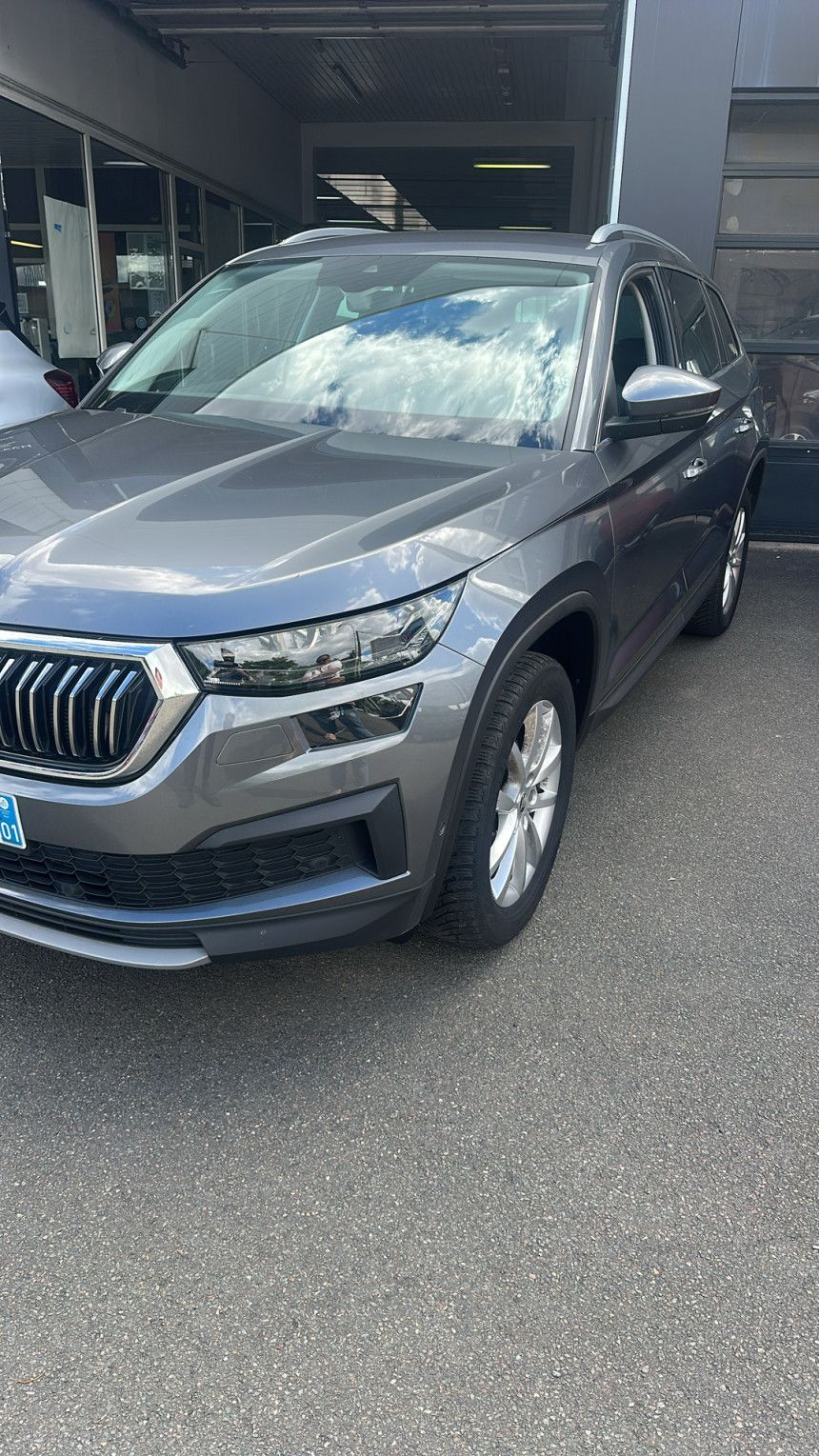 SUV gris stationné devant un bâtiment sur un parking couvert.