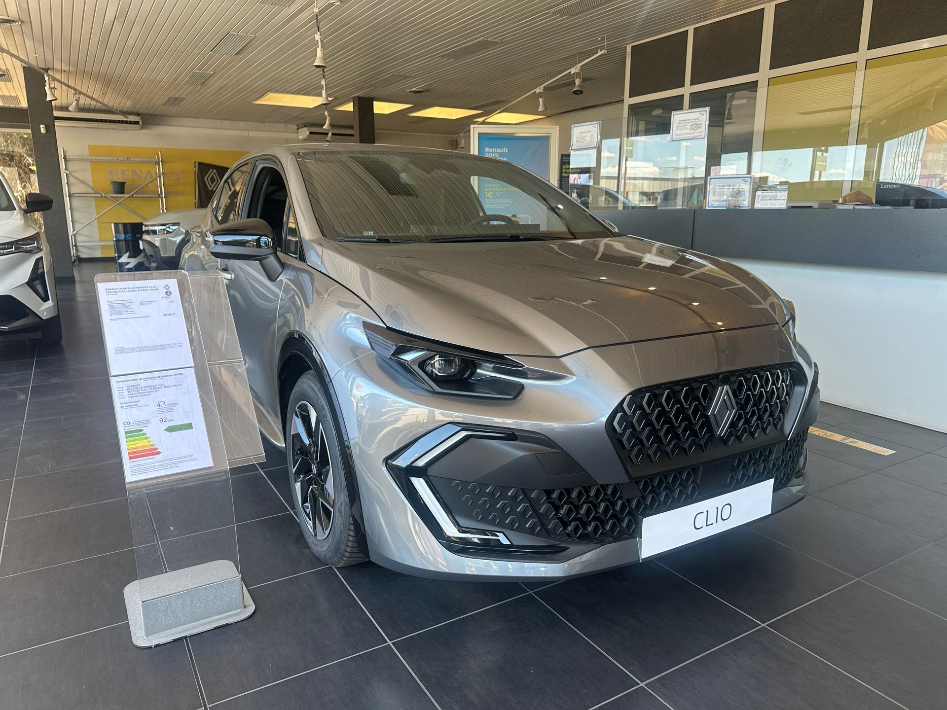 Un SUV argenté exposé dans une salle d'exposition, avec une pancarte publicitaire à côté.