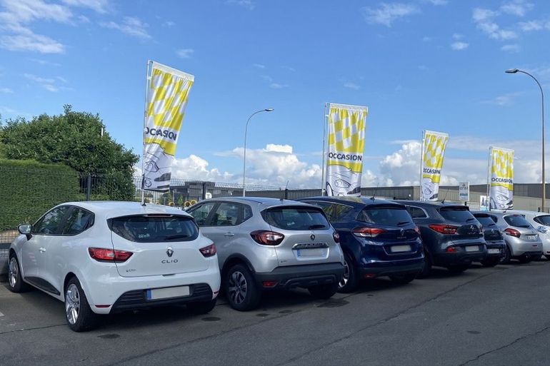 Des voitures garées en file indienne le long d'une route, des drapeaux jaunes flottant sous un ciel nuageux.