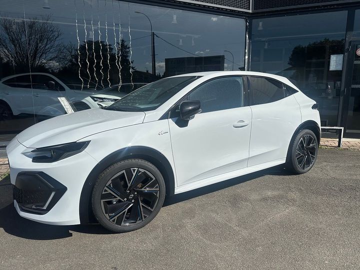 SUV blanc garé devant une concession automobile, avec jantes noires et vitres teintées.