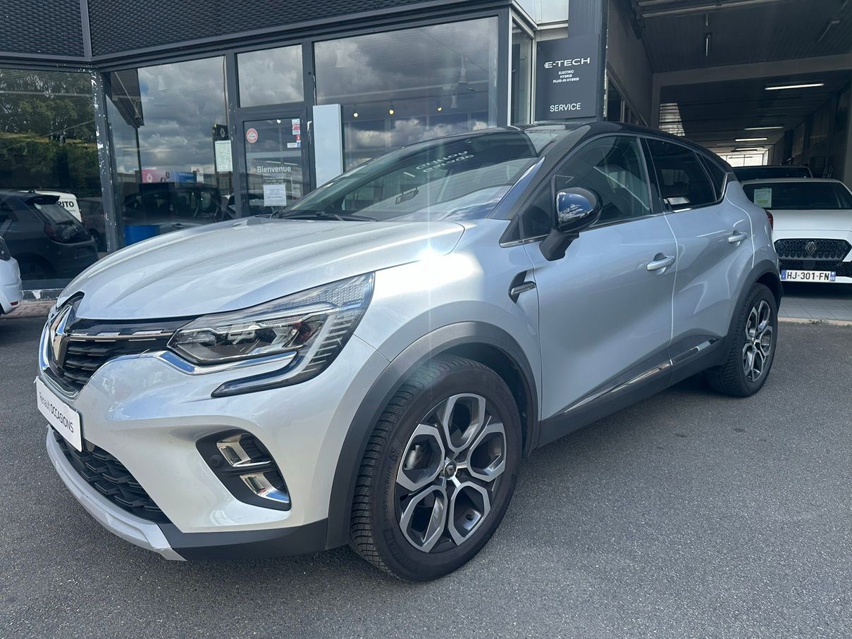 Renault Scenic argentée devant un garage.