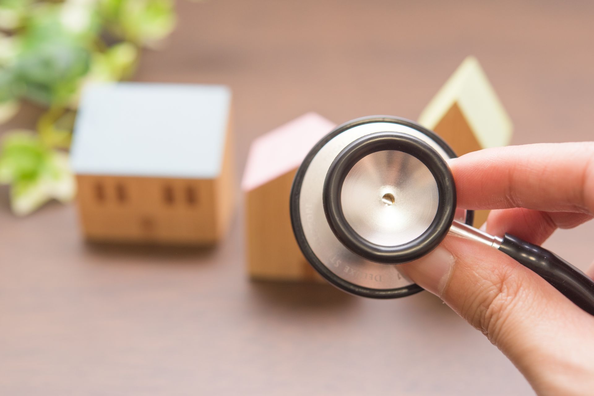 Main tenant un stéthoscope au-dessus d'une maison minature