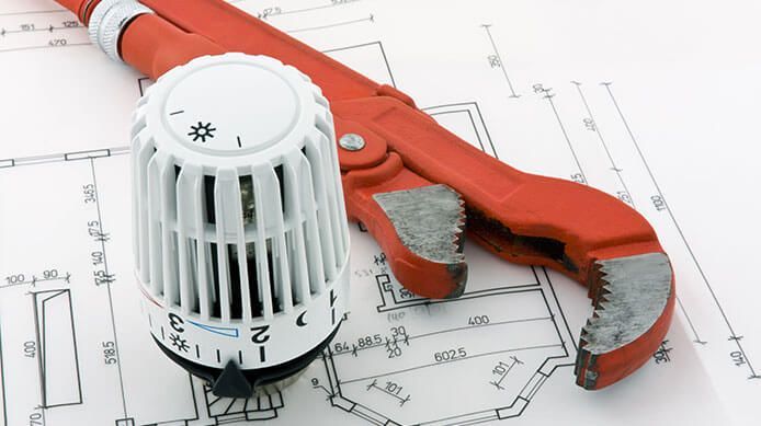 Clé à pipe rouge et robinet thermostatique de radiateur sur un schéma technique