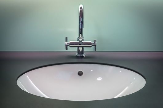 Vers plomberie Lavabo de salle de bain blanc moderne avec robinet chromé contre un mur vert menthe
