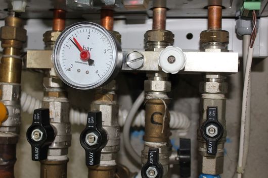 Vers chauffage Collecteur de plomberie avec manomètre, vannes et tuyaux en cuivre dans une buanderie