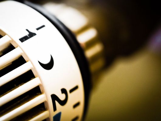 Vers chauffage Gros plan sur un cadran de thermostat blanc avec des chiffres noirs et un fond doré