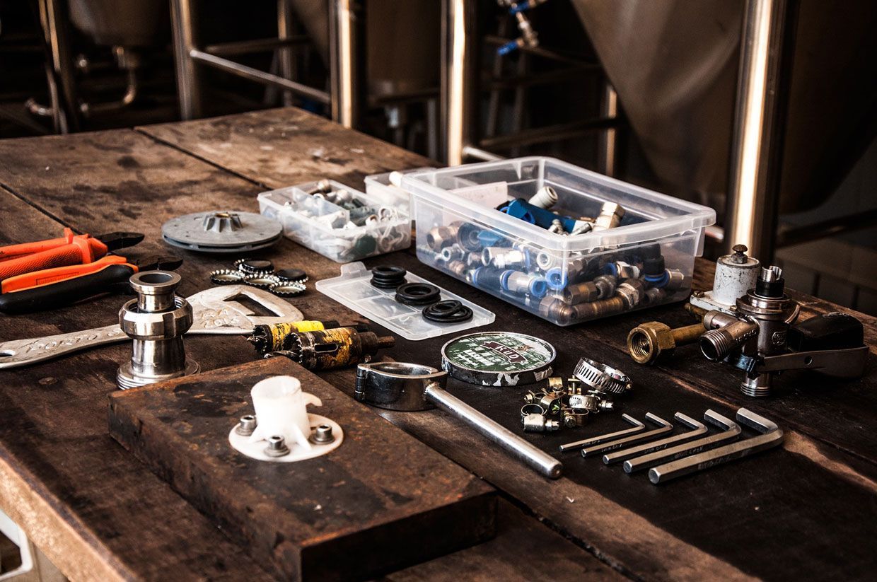 Des composants électroniques et des outils éparpillés sur un établi en bois dans un atelier sombre.