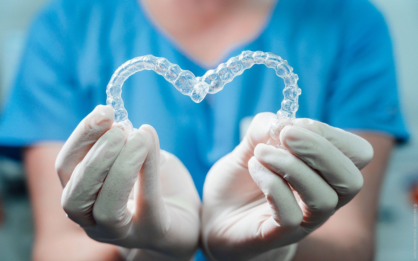 Eine Person hält einen durchsichtigen Retainer in Herzform in den Händen.