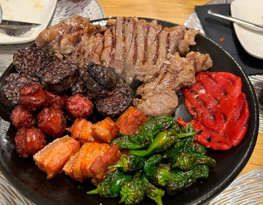 Un plato negro cubierto con carne y verduras sobre una mesa.