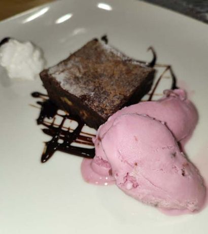 Un plato blanco cubierto con un brownie y helado.