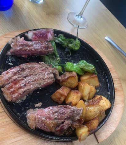Un plato de comida con carne y patatas en una mesa de madera.