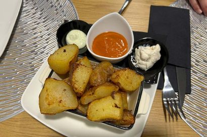 Un plato blanco cubierto de patatas y salsas sobre una mesa.