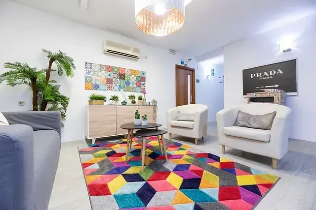 Una sala de estar con una alfombra colorida, sillas y un sofá.