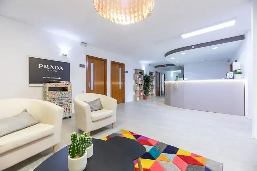 Una sala de estar con un sofá y sillas y un cartel que dice Prada.