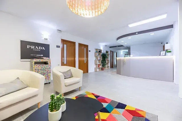 Una sala de estar con un sofá y sillas y un cartel que dice Prada.
