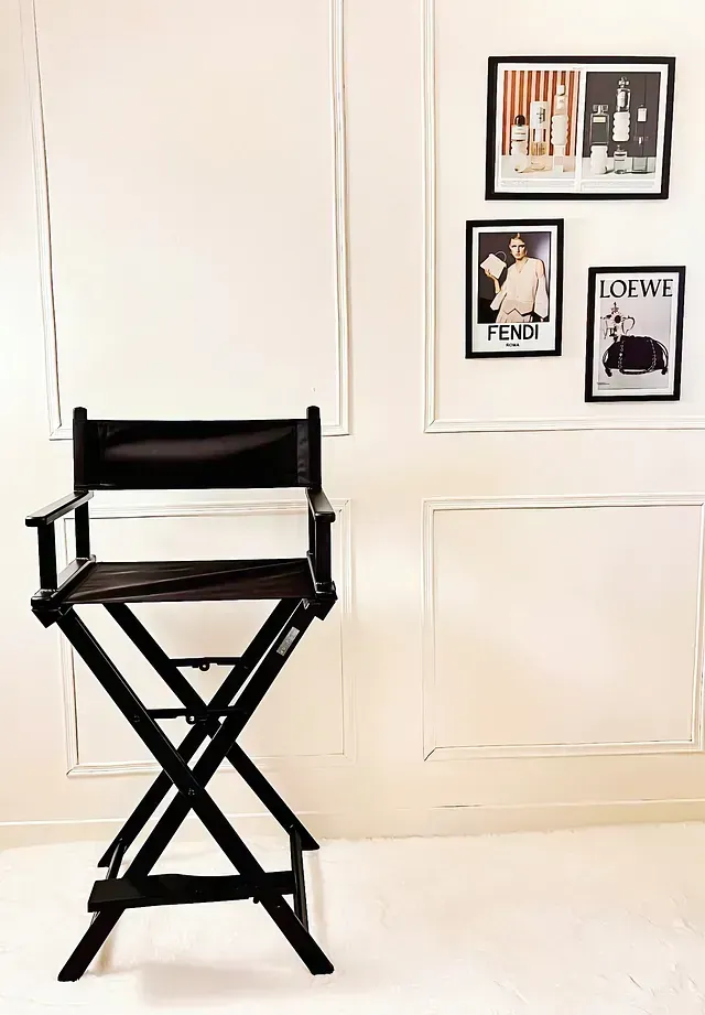 Una silla de director negra frente a una pared blanca