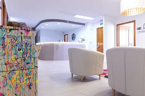 Una sala de estar con dos sillas y un cuadro en la pared.