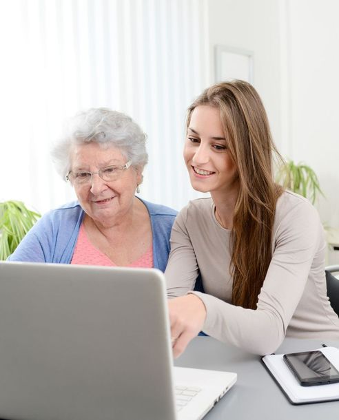 Une jeune personne aidant une personne âgée à utiliser un ordinateur