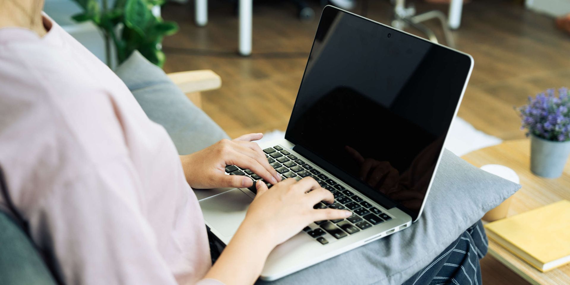 Una mujer está sentada en un sofá usando una computadora portátil.