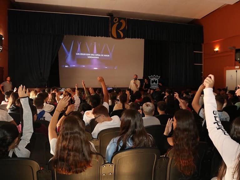 Un grupo de personas levanta las manos frente a una pantalla grande que dice vista