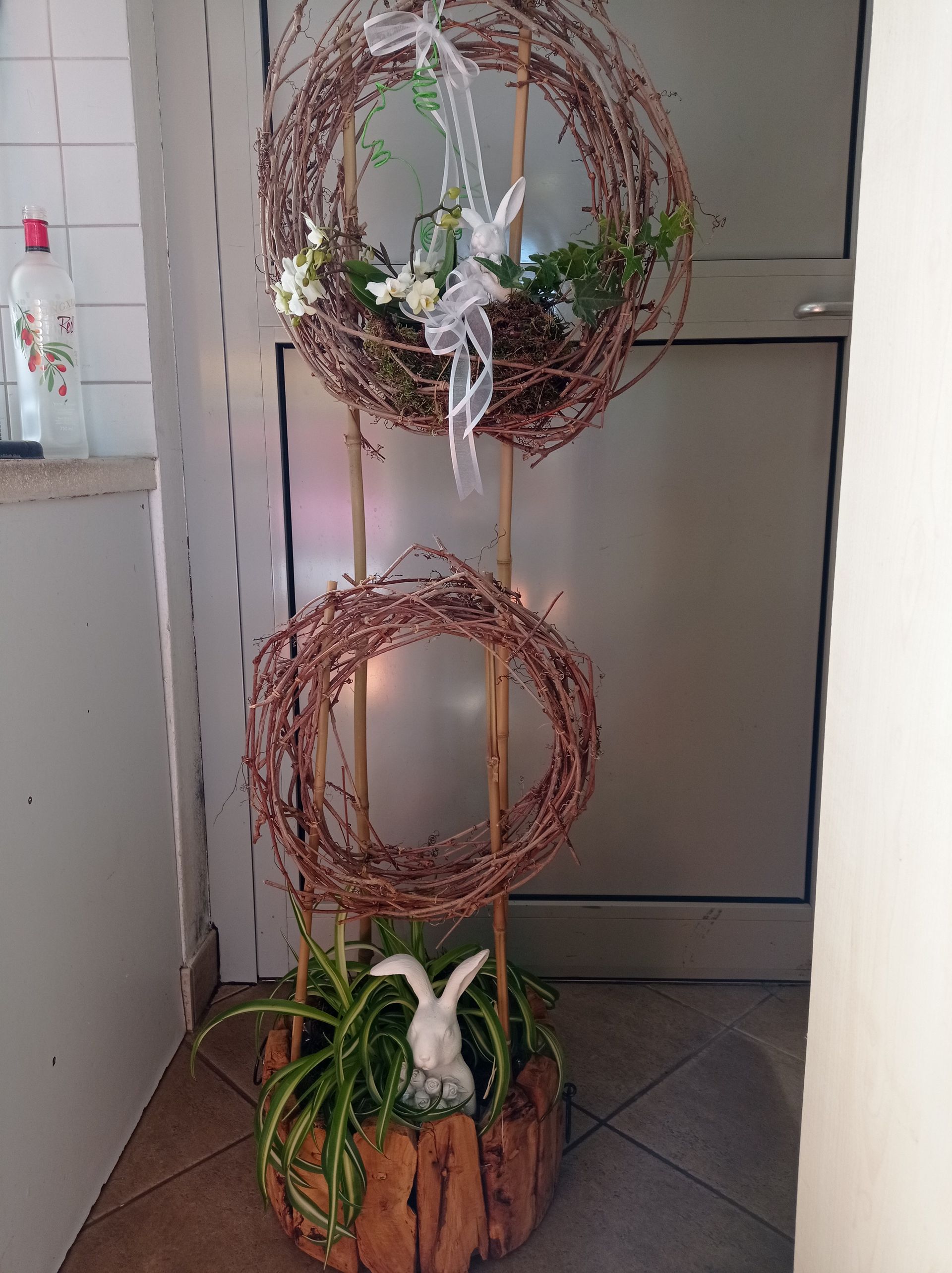 Osterkranzdekoration mit Hasenfigur und Grünpflanzen.