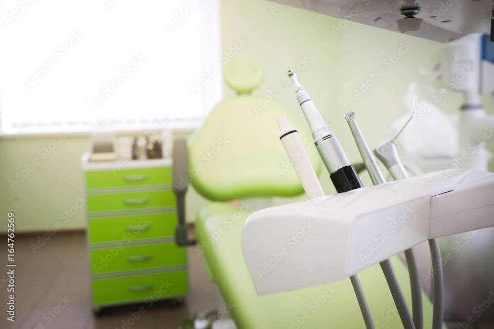 Poltrona odontoiatrica con strumenti e armadietti verdi in una luminosa sala clinica.