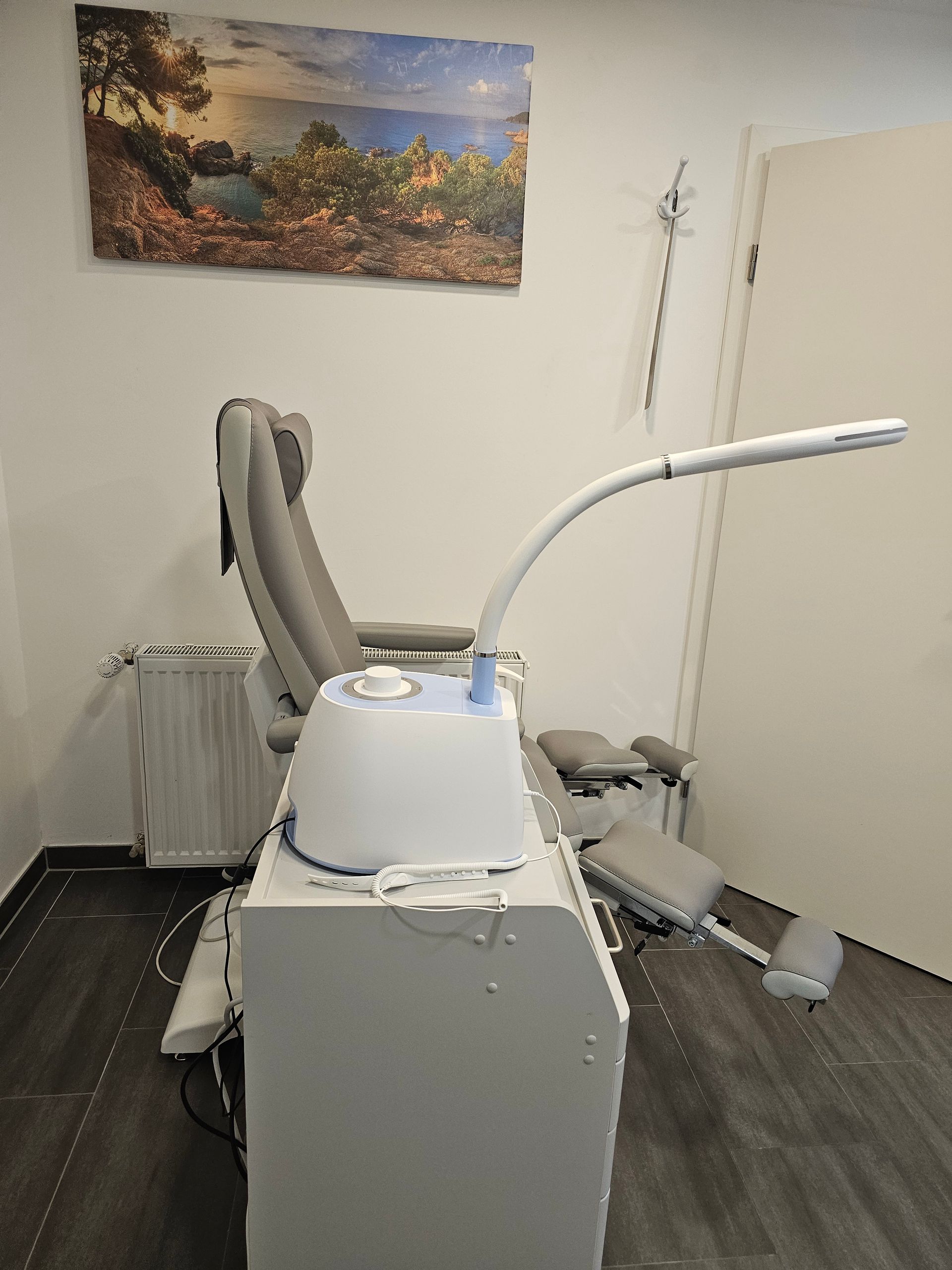 Zahnarztzimmer mit einem Röntgengerät im Vordergrund und einem Stuhl an der Wand.