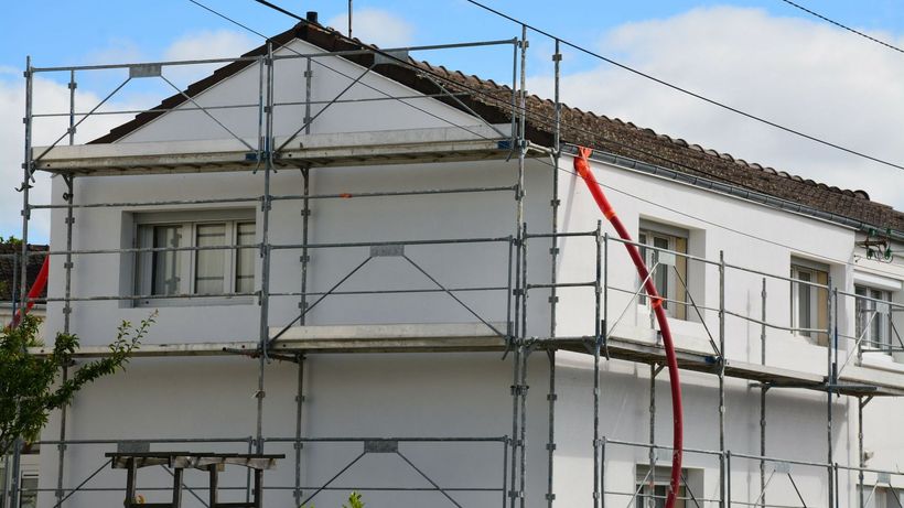 Échafaudage installé autour d'une maison aux murs blancs
