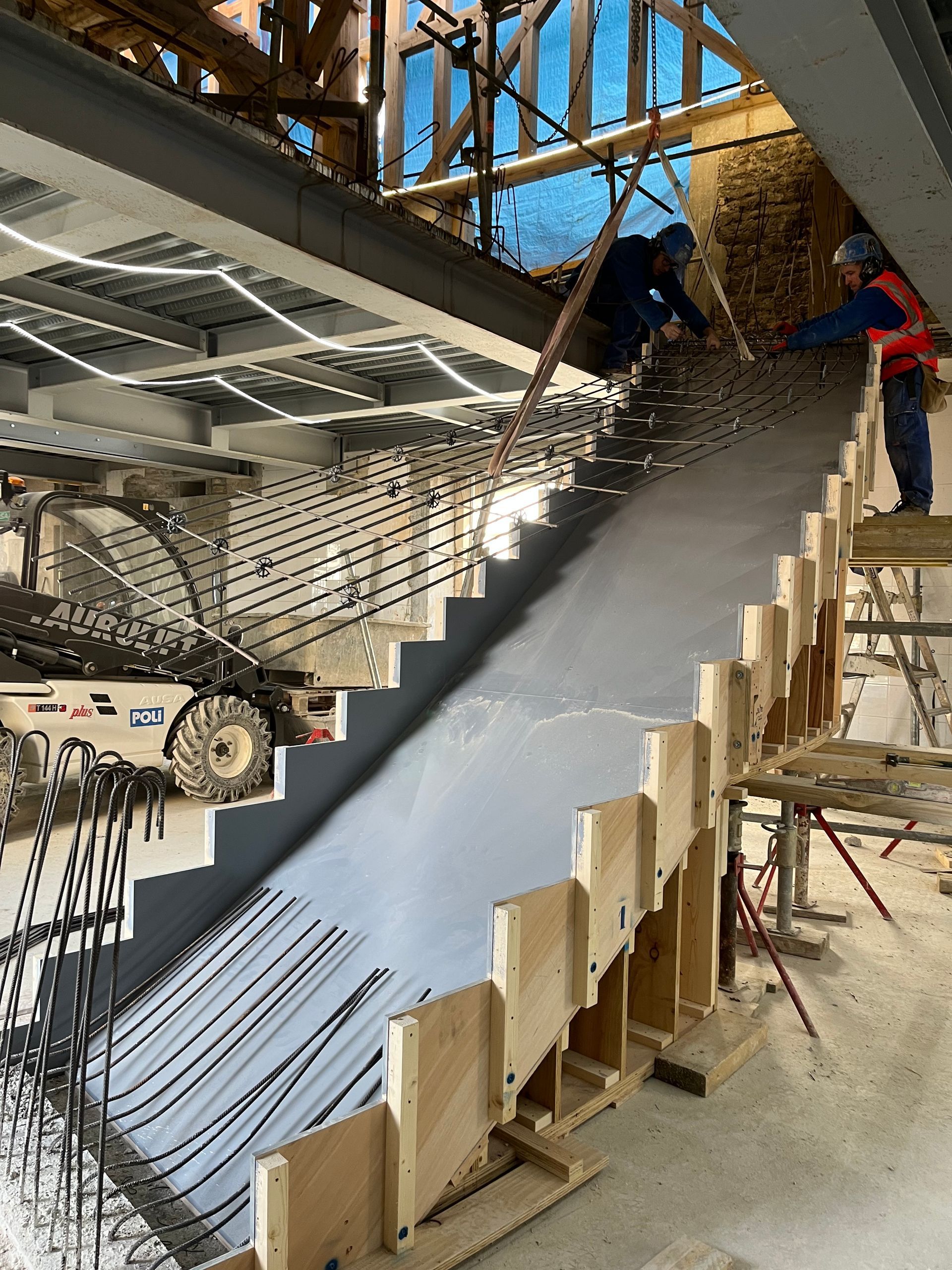 Escalier en construction avec des structures en bois et métal et une chape béton.