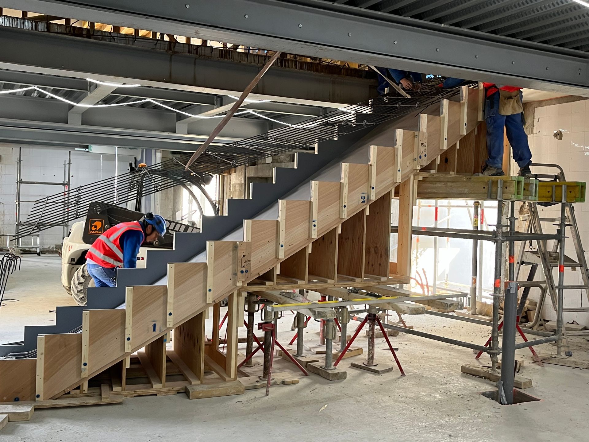 Escalier en construction avec des structures en bois et métal et nombreux renforts.